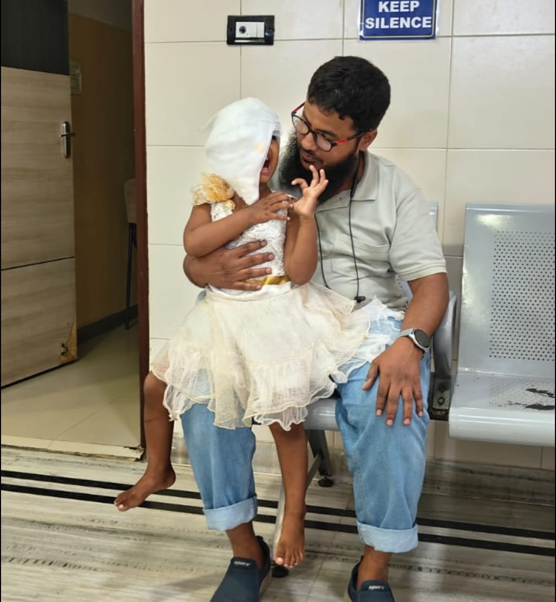 A volunteer comforting a bandaged child in a hospital waiting area